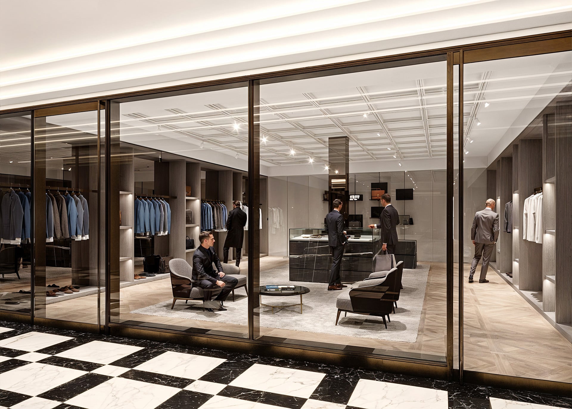 Luxury clothing store with suits displayed, people browsing inside.