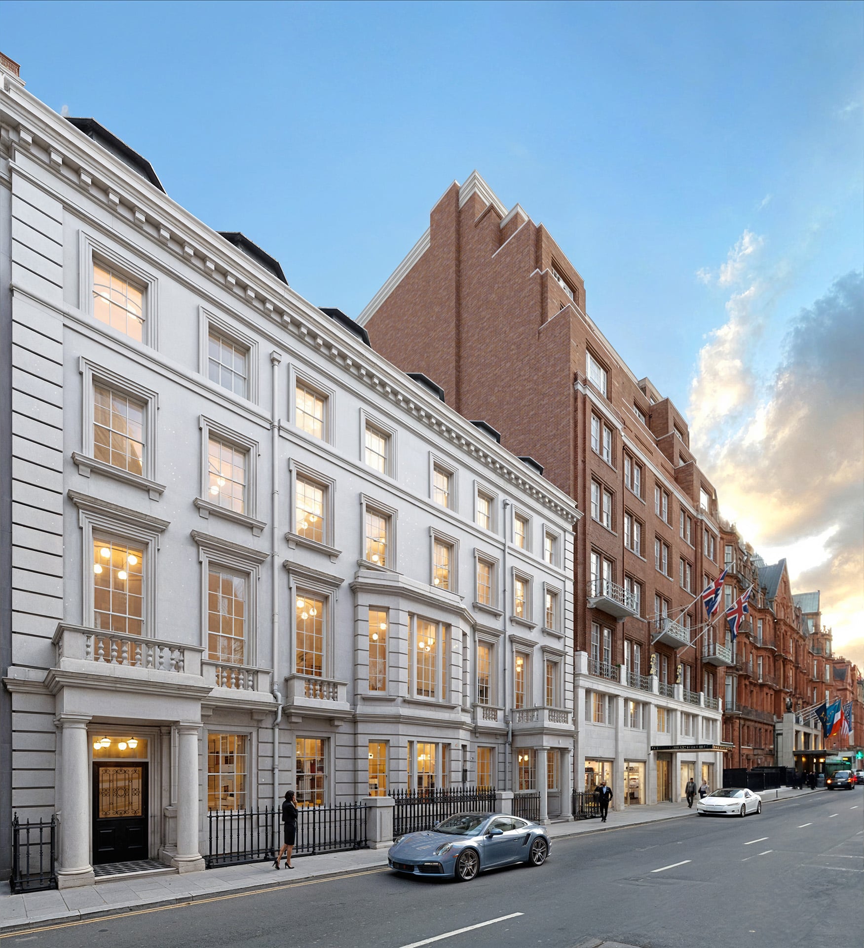 Street view of elegant buildings with cars parked along the road under a partly cloudy sky.