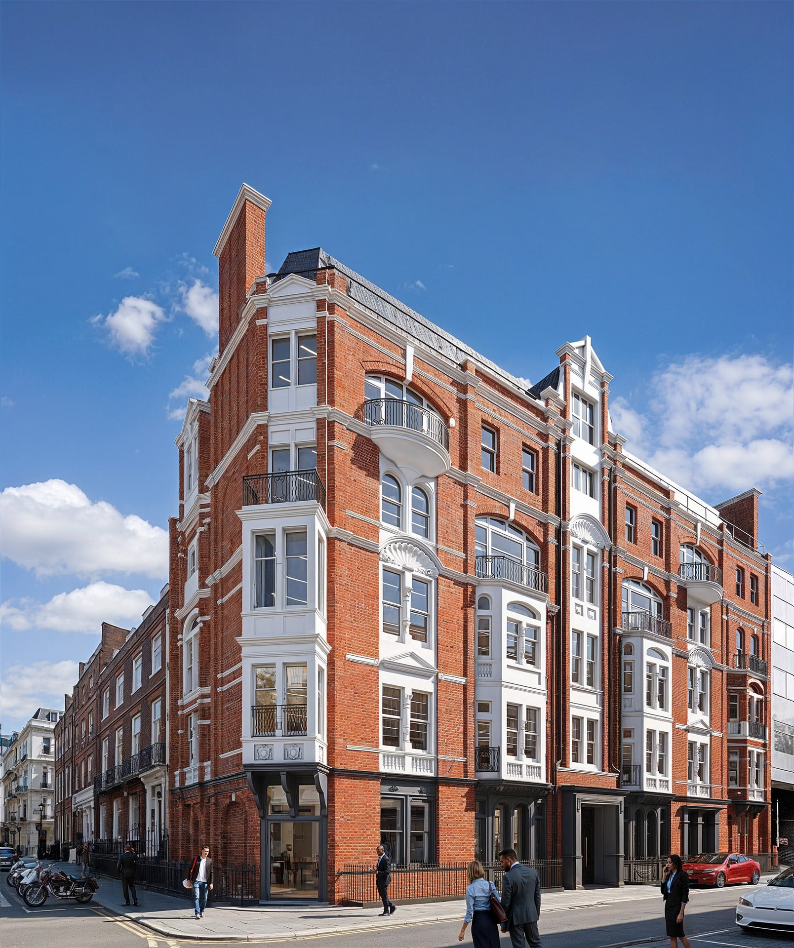 A red brick Victorian building under a blue sky, with people on the sidewalk.