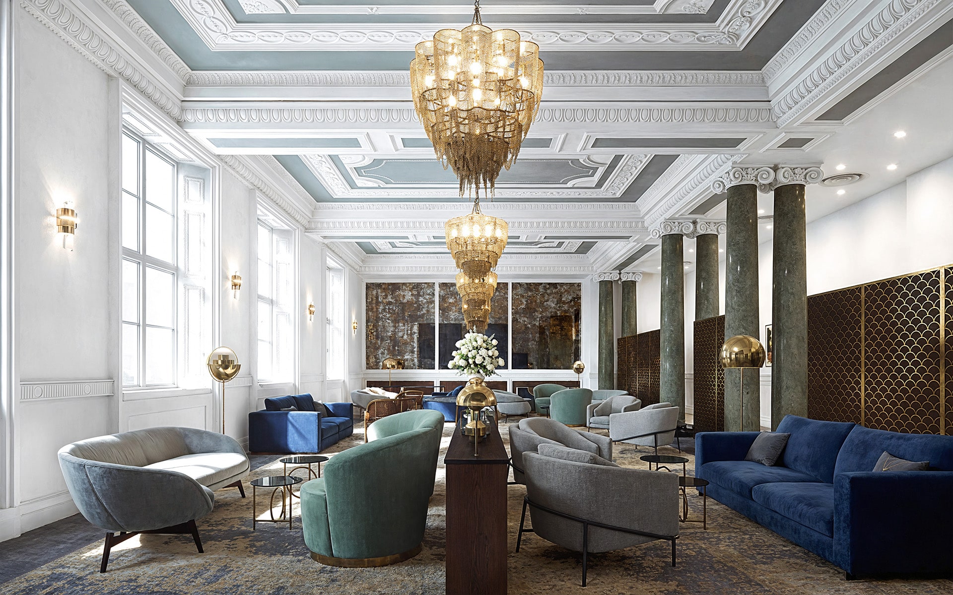 Elegant lounge with chandeliers, comfortable seating, and ornate ceiling details.