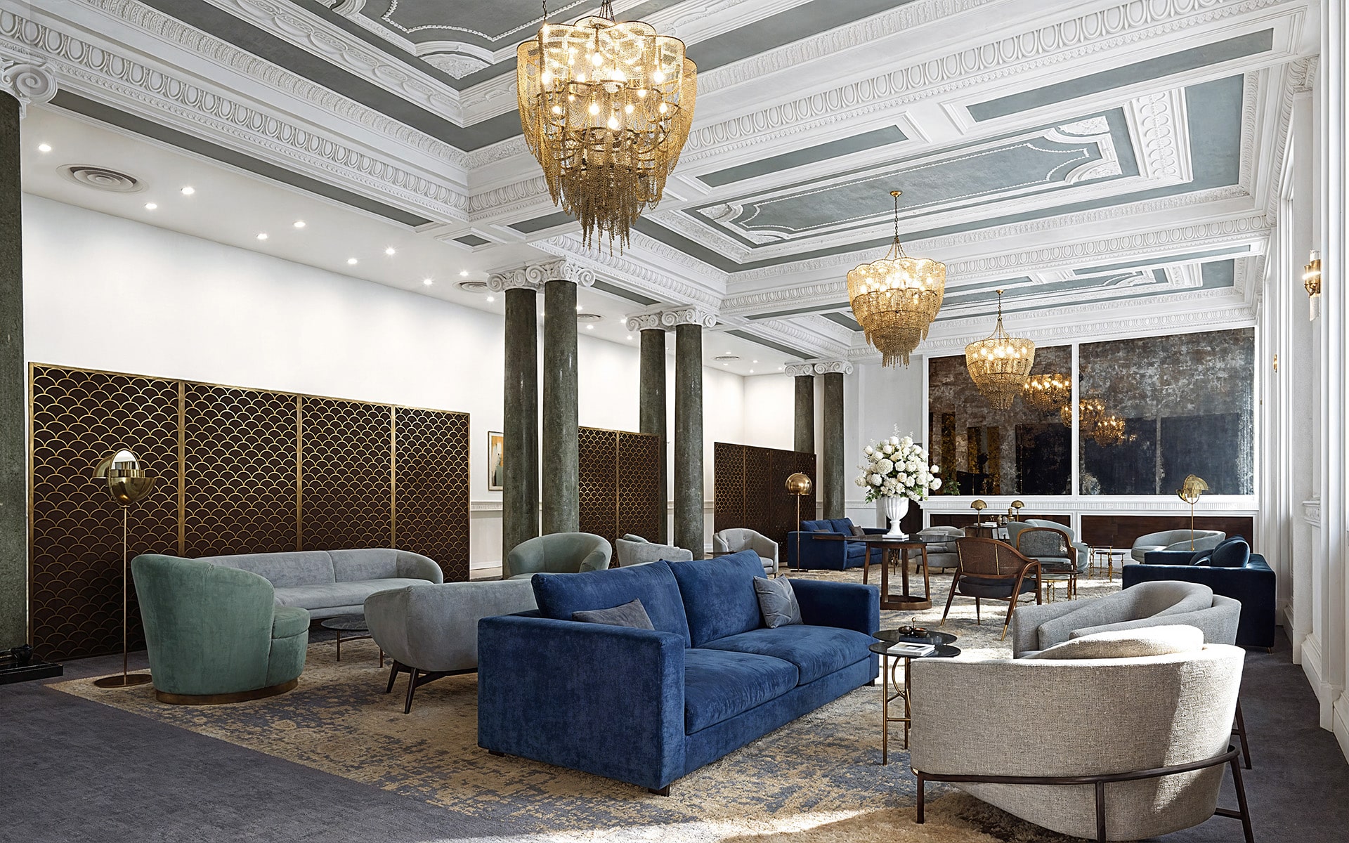 Elegant lounge with chandeliers, plush sofas, and high ceilings.